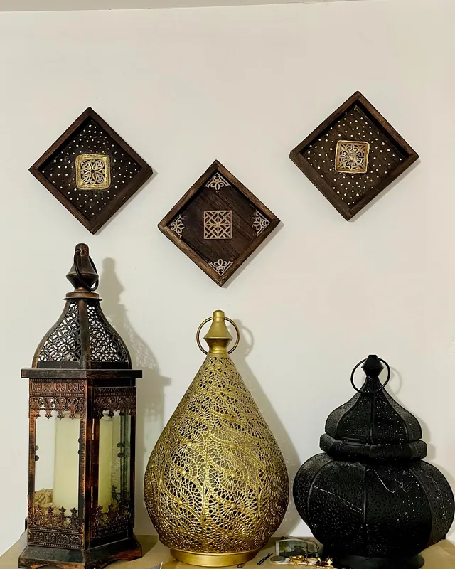 Three small diamond wooden frames on a wall above lanterns
