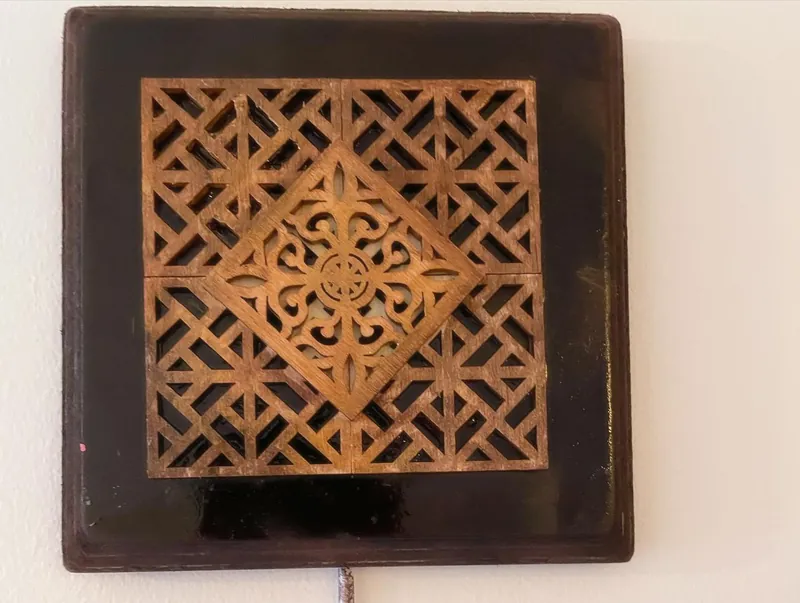Dark wooden plaque with a large geometric lattice cut-out